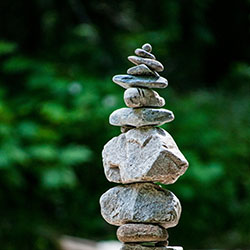 A stack of rocks forms a cairn amidst a green landscape