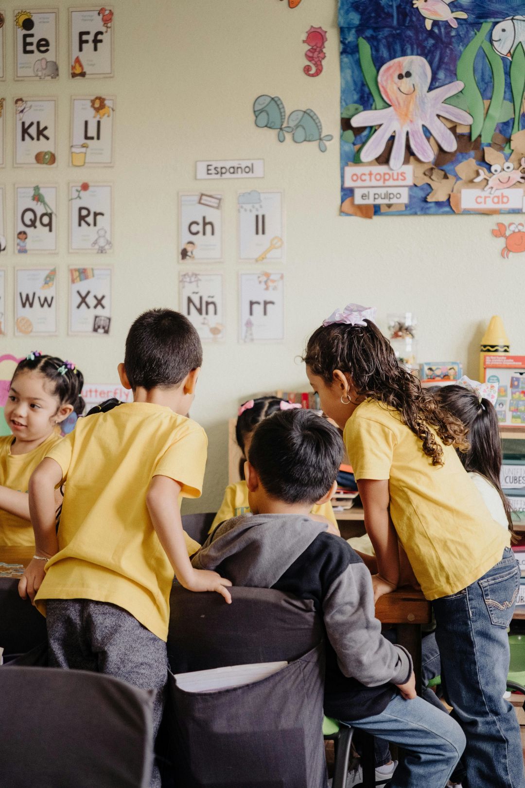 Children crowded around a desk in a classroom